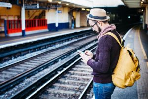 man using smart phone at train stop